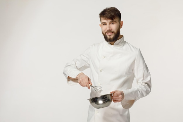 gentil et beau cuisinier tient des ustensiles de cuisine sur un fond blanc isolé concept pour un cuisinier