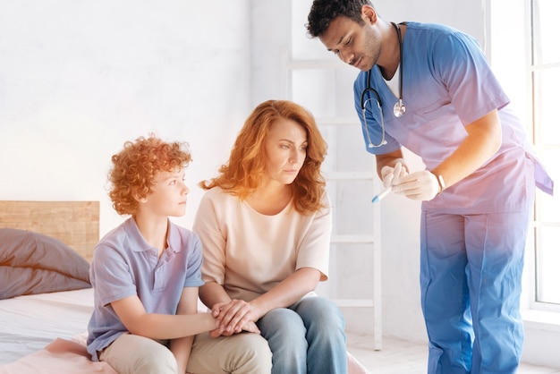 Gentil docteur debout près du patient et inclinant la tête tout en démontrant le résultat