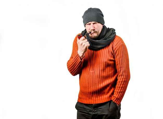 Un gentil homme d'âge moyen avec une barbe, dans un bonnet tricoté, fumant une pipe