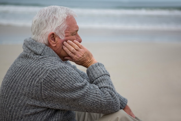 Gentil homme senior assis sur la plage