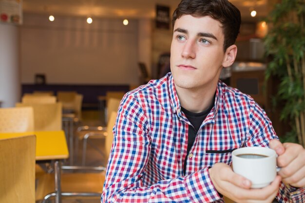 Gentil jeune homme tenant une tasse de café