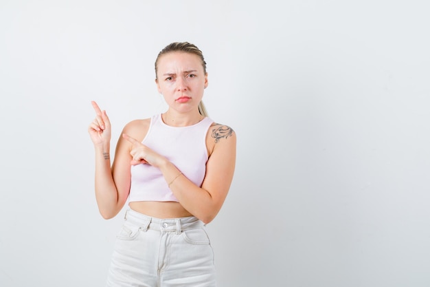 La gentille fille montre le côté gauche sur le fond blanc