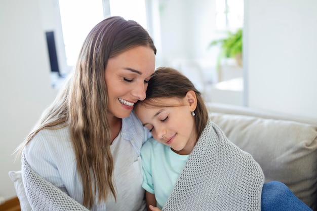 Une gentille fille et sa mère profitent d'une matinée ensoleillée Bon temps à la maison L'enfant se réveille du sommeil Famille jouant sous une couverture sur le lit dans la chambre