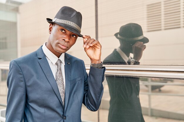 Gentleman afro-américain en costume agitant avec la main sur le chapeau