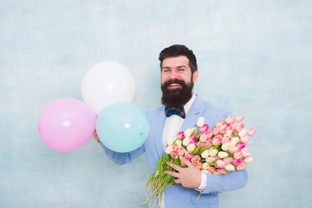 Gentleman rendez-vous romantique Salutations d'anniversaire Livraison de fleurs Pour quelqu'un de spécial Homme barbu costume noeud papillon tenir des ballons à air et un bouquet Gentleman faisant une surprise romantique pour elle