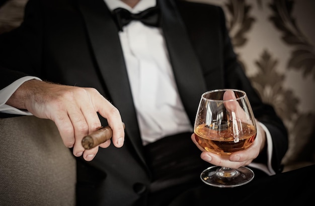 Gentleman tenant un verre de cognac et de cigare