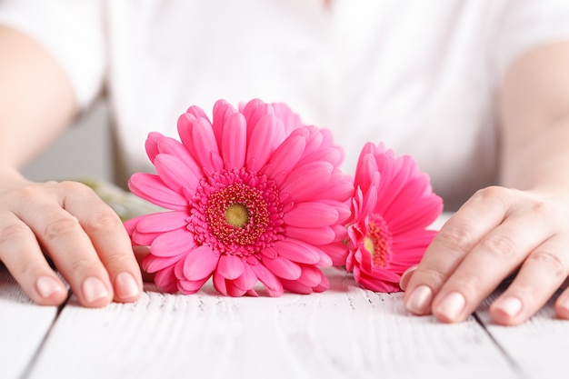 Gerbera fleur rose dans les mains des femmes, vue rapprochée concept de soins aux femmes