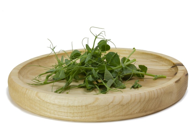 Germes de pois microgreens dans un bol en bois Pousses vertes de jeunes plants de yak pousses d'une plante savoureuse et utile Macro photo de gros plan de nourriture sur fond blanc vue latérale