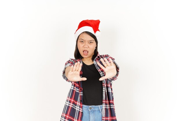 Geste d'arrêt ou de rejet d'une femme asiatique portant une chemise à carreaux rouge et un chapeau de père Noël isolé sur blanc
