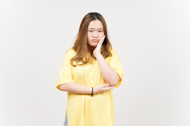 Geste ennuyeux de belle femme asiatique portant un t-shirt jaune isolé sur fond blanc