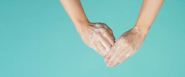 Geste de lavage des mains avec du savon moussant pour les mains sur fond vert menthe ou bleu Tiffany.