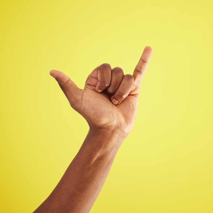 Photo geste de la main et shaka avec la personne en studio sur fond jaune se sentant insouciant close-up emoji signe et signal avec modèle africain salut acclamation ou victoire surf pour de bonnes nouvelles ou victoire