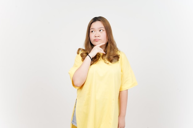Geste de pensée de belle femme asiatique portant un T-shirt jaune isolé sur fond blanc