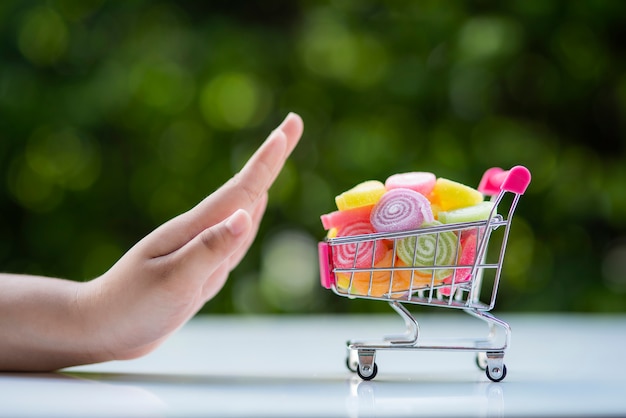 Les gestes de la main d'une femme pour rejeter les bonbons en couleur qui sont mis dans le panier