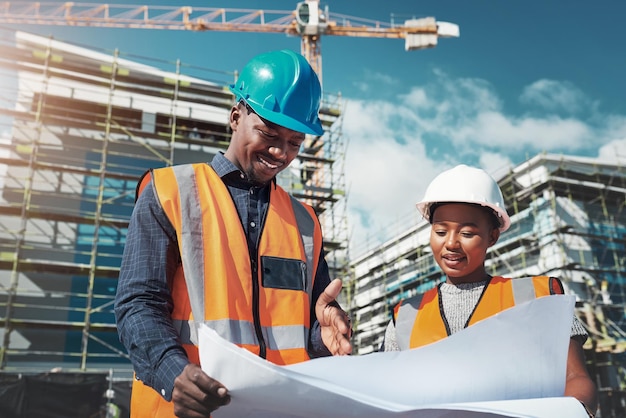 La gestion d'un chantier est un effort conjoint Photo d'un jeune homme et d'une femme examinant des plans de construction sur un chantier de construction