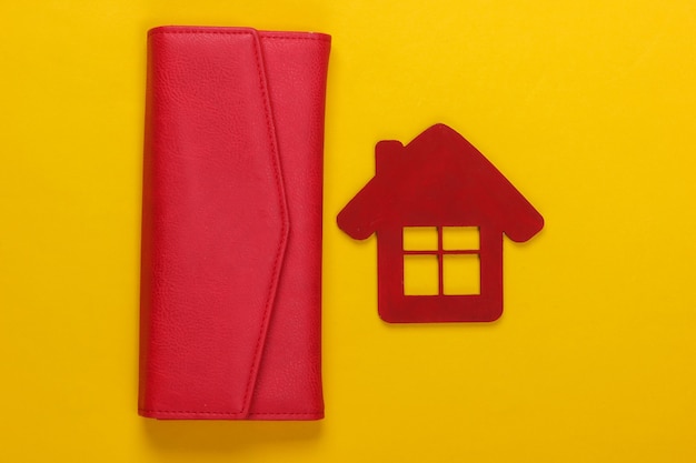 Gestion du budget familial. Figurine d'une maison avec portefeuille sur jaune