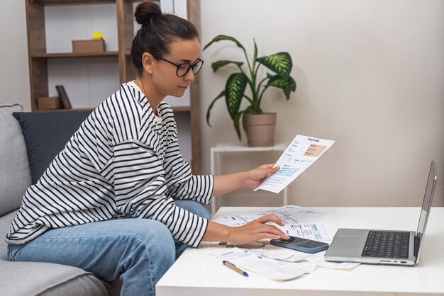 Gestion financière domestique femme factures de services publics documents fiscaux paiements mensuels dans le salon