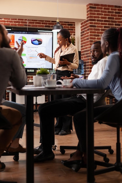 Gestionnaire afro-américain montrant une présentation marketing expliquant le partenariat commercial de planification de stratégie d'entreprise travaillant dans le bureau de démarrage. Diverses idées de projets de remue-méninges en équipe