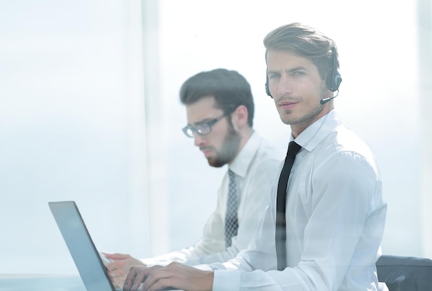 Le gestionnaire avec le casque utilise un ordinateur portable pour travailler avec la photo du client avec un espace de copie