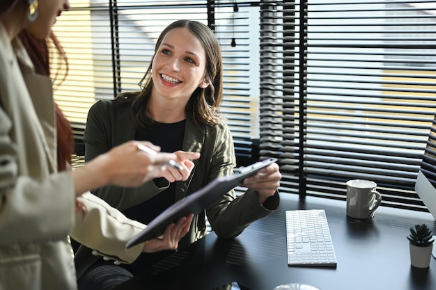 Photo gestionnaire caucasienne souriante expliquant la stratégie du projet discutant du travail avec un collègue dans un bureau moderne