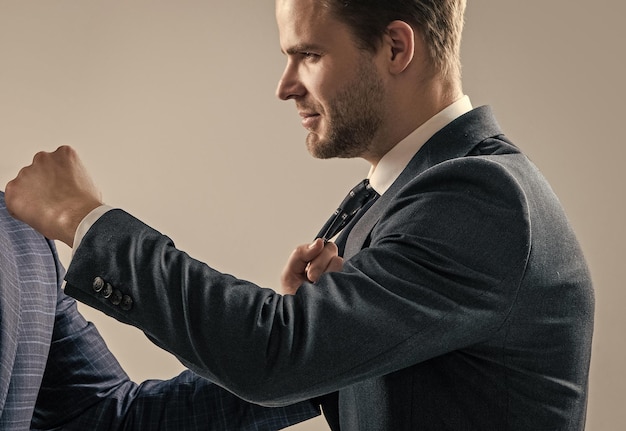 Le gestionnaire a un combat de poing avec un adulte de sexe masculin en tenue de soirée sur fond gris