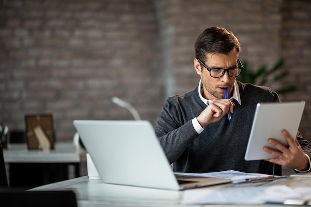 Gestionnaire concentré lisant un e-mail sur le pavé tactile tout en travaillant sur un projet au bureau