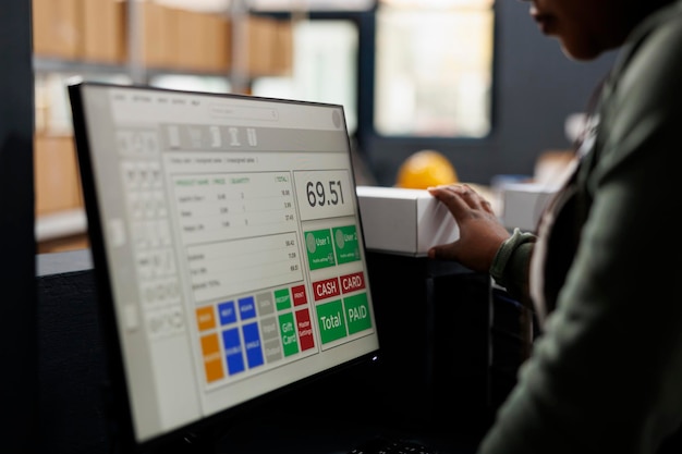 Photo gestionnaire examinant les détails de livraison des produits sur ordinateur, travaillant sur les commandes des clients préparant les colis au comptoir de l'entrepôt. travailleur afro-américain analysant la logistique des marchandises