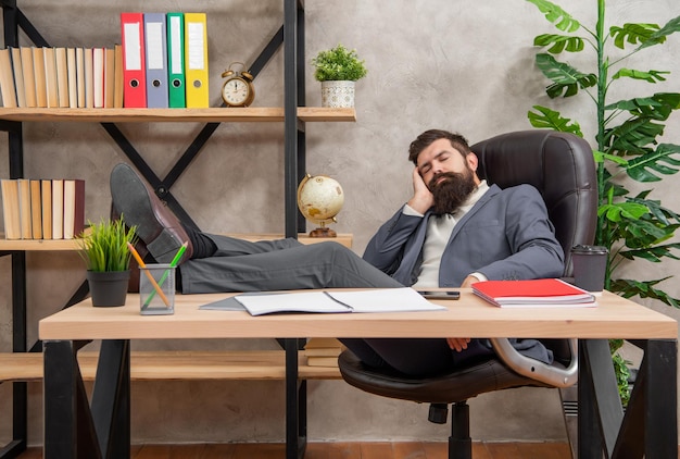 Gestionnaire fatigué faisant la sieste avec les jambes sur le bureau pendant le repos de travail dans la sieste du bureau