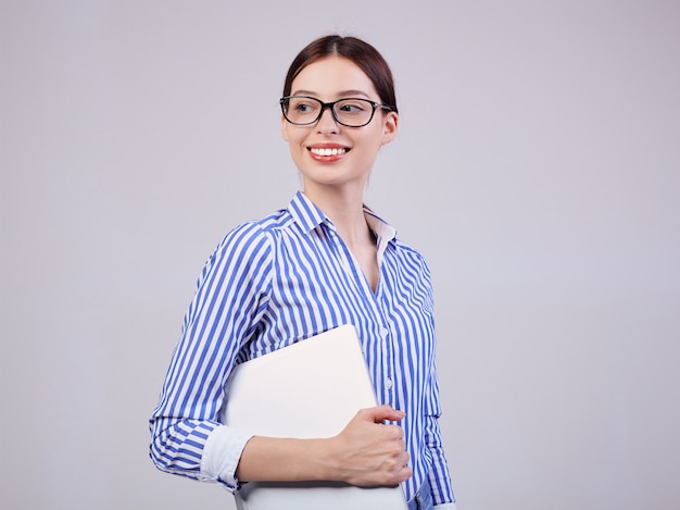 gestionnaire de femme dans une chemise rayée blanc-bleu avec des lunettes et un ordinateur portable sur gris. Employé de l'année, femme d'affaires.