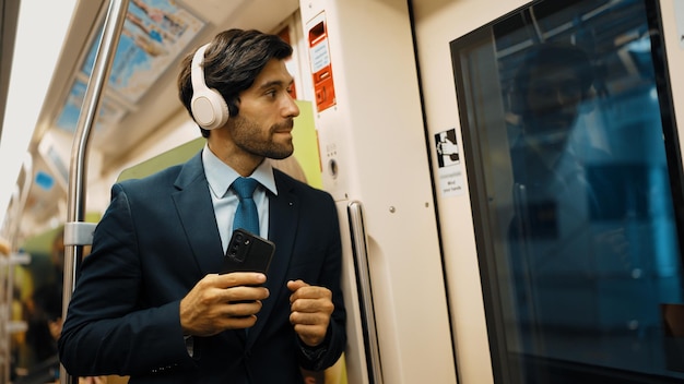 Photo un gestionnaire intelligent porte des écouteurs et écoute de la musique alors qu'il se tient dans le train exultant.