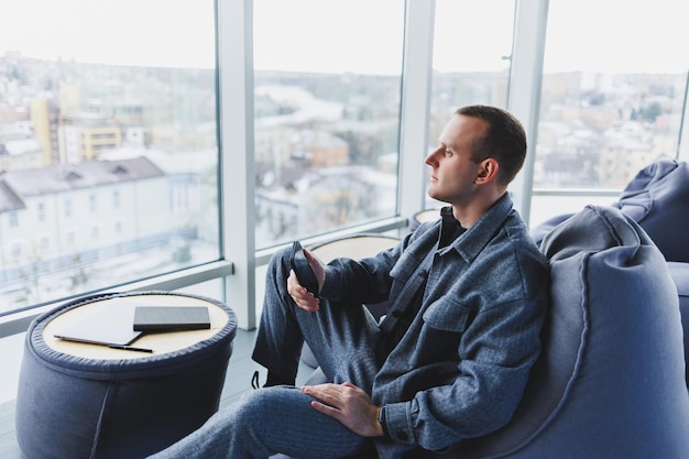 Gestionnaire masculin confiant assis dans un espace de travail moderne devant un ordinateur portable et parlant au téléphone travail à distance