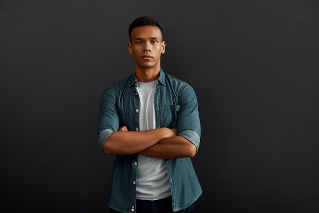 Gestionnaire parfait beau et jeune homme afro-américain regardant la caméra et gardant les bras croisés