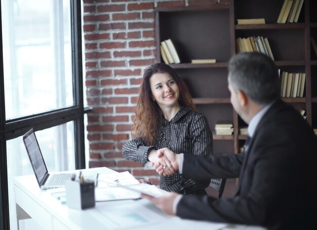 Gestionnaire de poignée de main et client assis à votre bureau