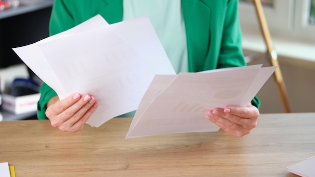 Gestionnaire tenant de nombreux documents dans les mains alors qu'il était assis au bureau de travail femme d'affaires regarde