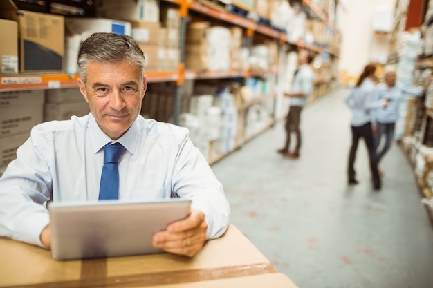 Gestionnaire travaillant sur tablet pc tout en regardant la caméra