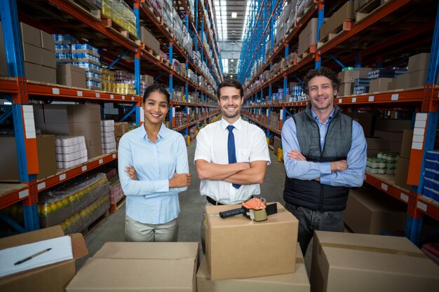 Les gestionnaires heureux posent devant des boîtes en carton avec les bras croisés