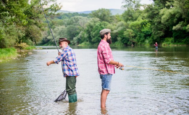 Get Hobby passe-temps et activité sportive Appât à truite amitié masculine famille liaison deux pêcheurs heureux avec canne à pêche et filet week-end d'été hommes mûrs pêcheur père et fils pêchant