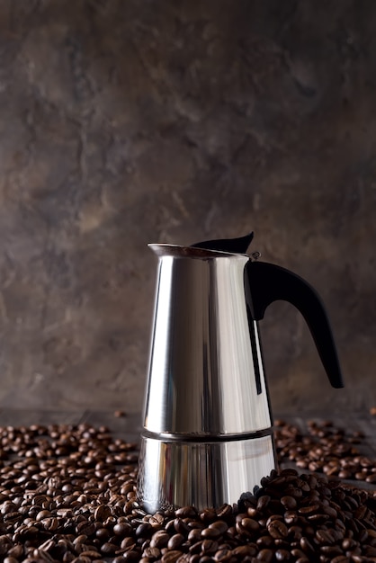 Geyser cafetière sur le fond de grains de café sur un fond en bois foncé, espace copie