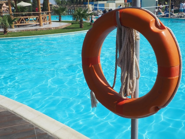 Un gilet de sauvetage est suspendu à un poteau près d'une piscine.