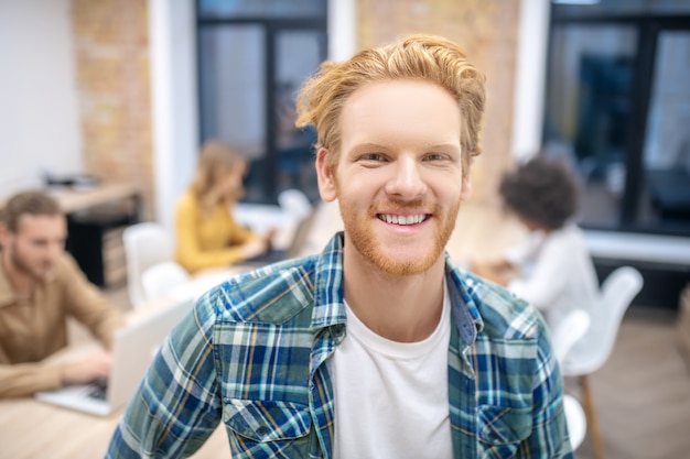 Ginger guy. Gingembre souriant dans une chemise à carreaux à la recherche de plaisir