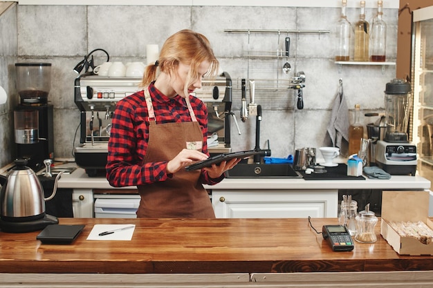 Girl Barista travaillant au café garde la tablette dans ses mains