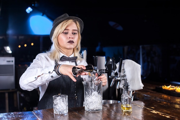 Girl barman formule un cocktail derrière le bar