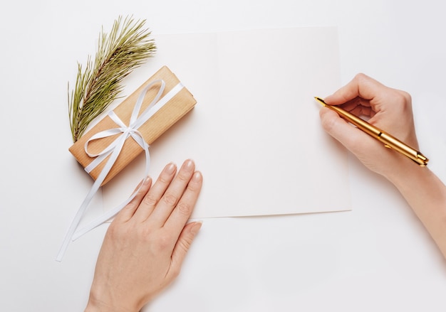 Girl écrit une note vierge avec une branche d'épinette et un stylo or