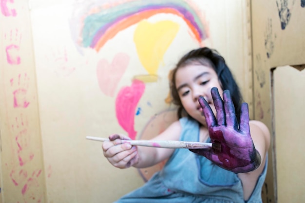 Girl Hand tient un pinceau pour dessiner sur du papierLeçon d'art adorable petite fille souriant joyeusement tout en profitant d'une leçon d'art et d'artisanat dans Paper Box House