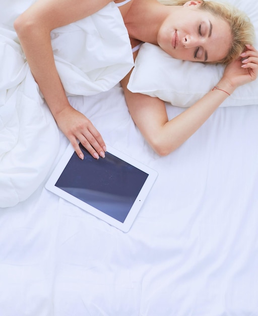 Girl holding digital tablet avec écran blanc et souriant à la caméra dans la chambre