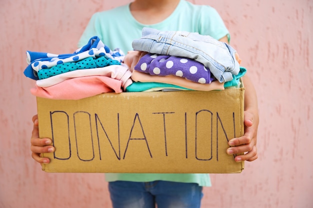 Girl holding donation box avec des vêtements d'été.