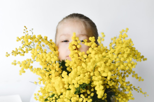 Girl holding mimosa sur un fond de mur blanc