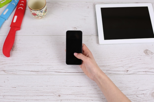 Girl holding Phone tablet allongé sur la table en bois