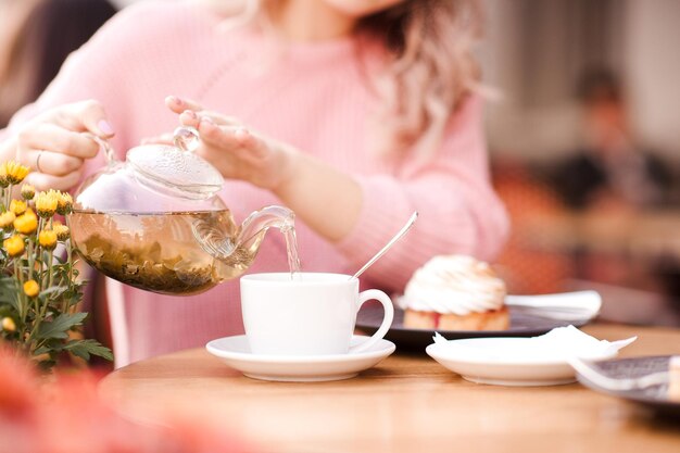 Girl holding pot avec du thé vert sur le café en plein air libre