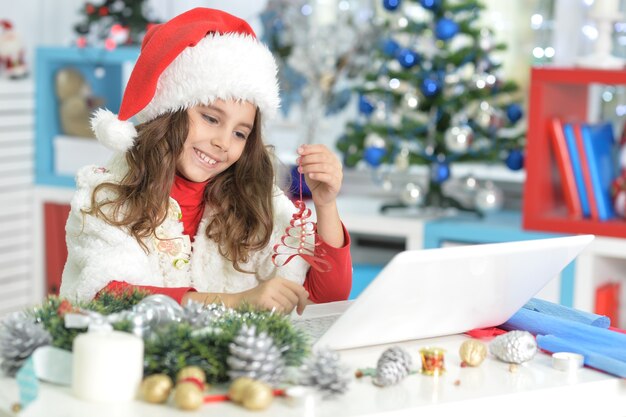 girl in Santa hat se préparant pour Noël en faisant des décorations faites à la main